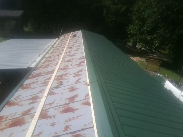 Old rusted panels beside newly installed green metal roofing — Wind Damage Roof Repair by Roofing Brothers in Osseo