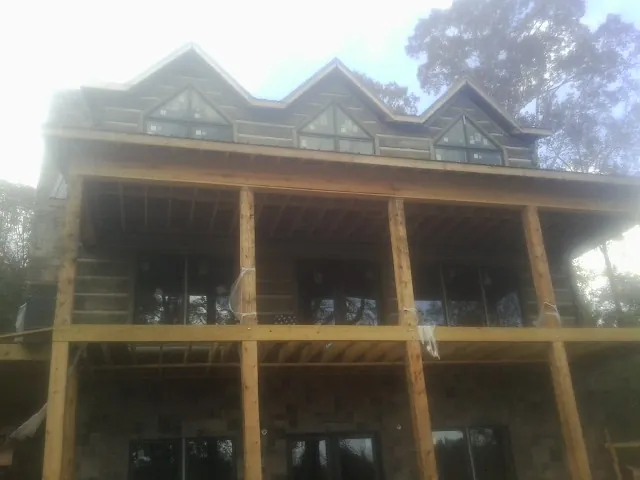 Dormers and porch framing on a large log home under construction — Roof Coating work by our crew in Osseo
