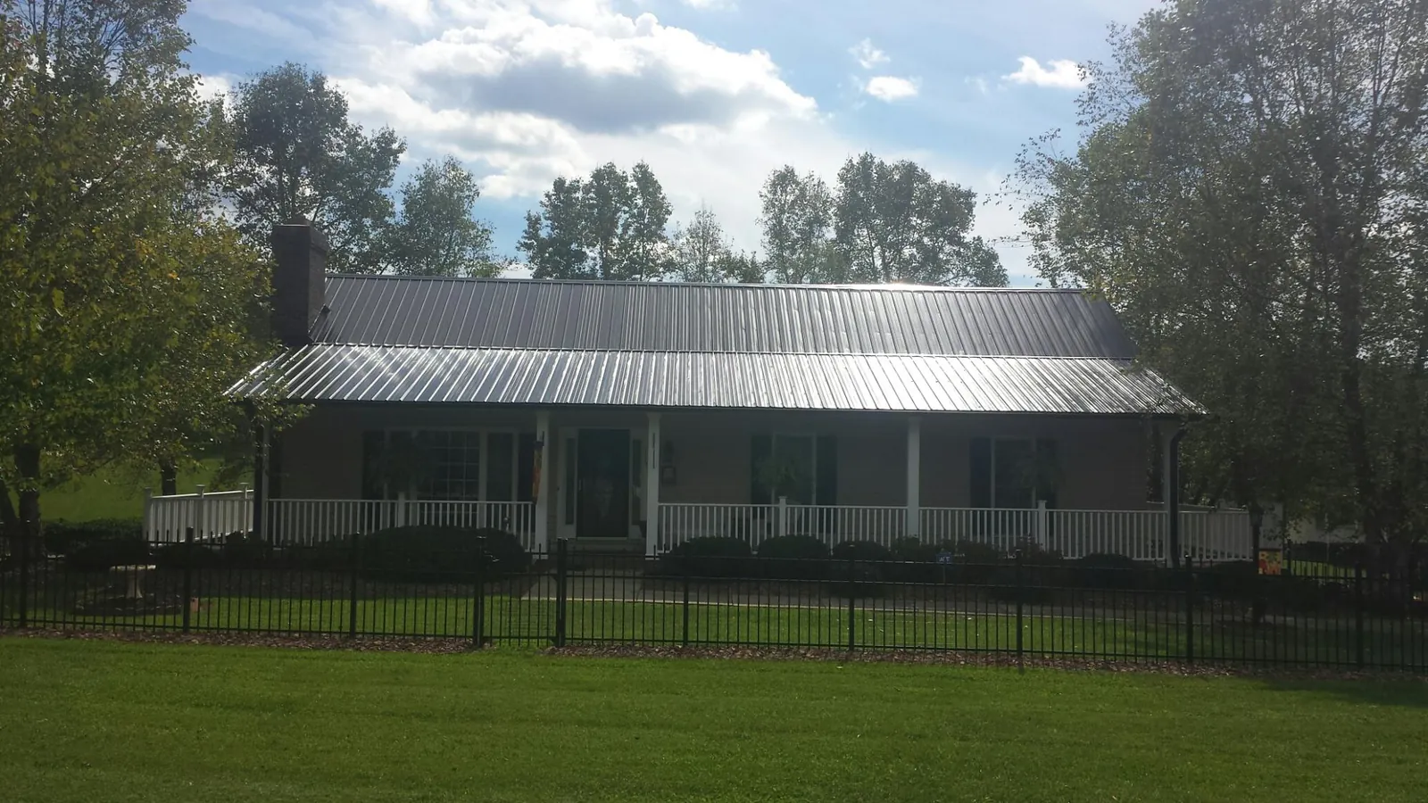 Gray metal roof on a brick ranch with a full width front porch — Gutter Guard Installation work by our crew in Osseo