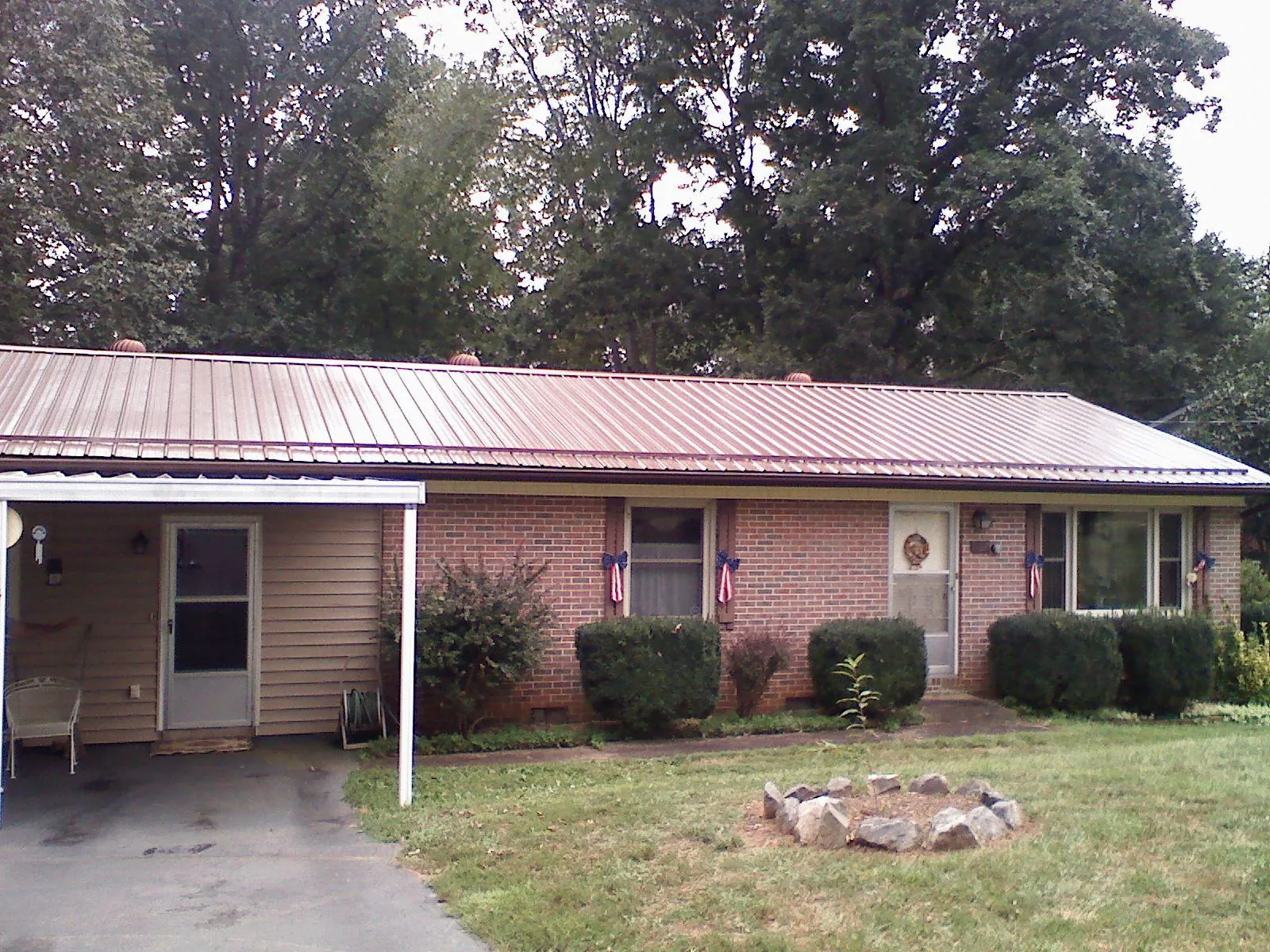 Bronze metal roof and carport on a brick ranch home — Roof Repair work by our crew in Osseo